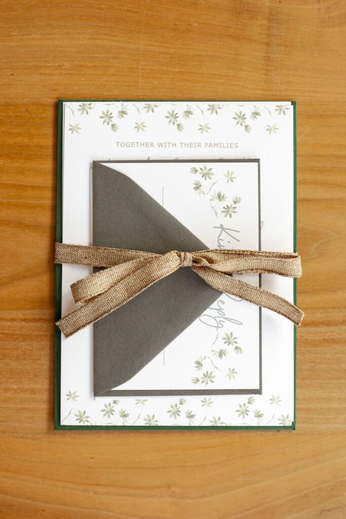 Natural-themed destination wedding invitation tied with rustic ribbon