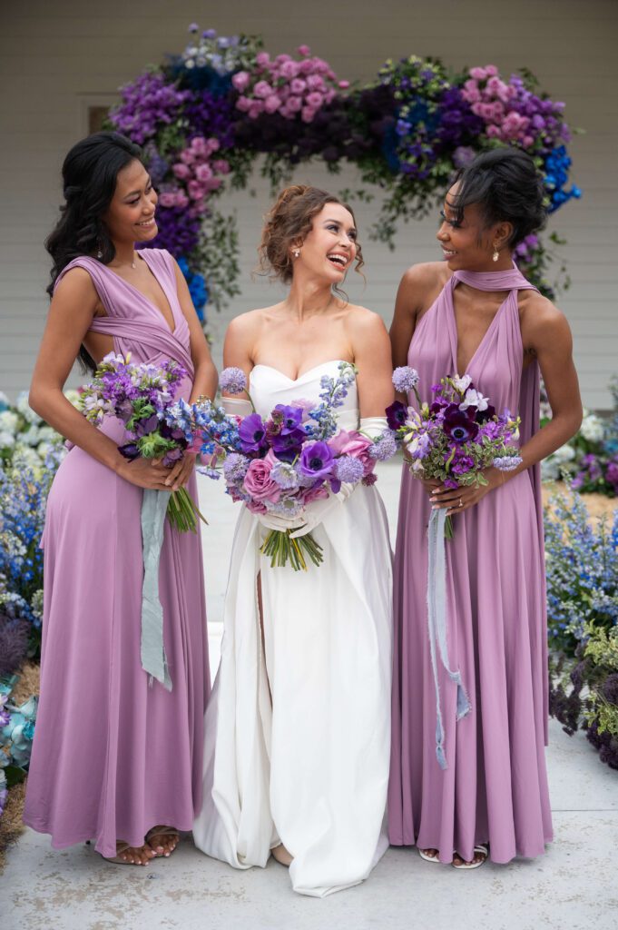 Bride with bridesmaids holding vibrant purple bouquets