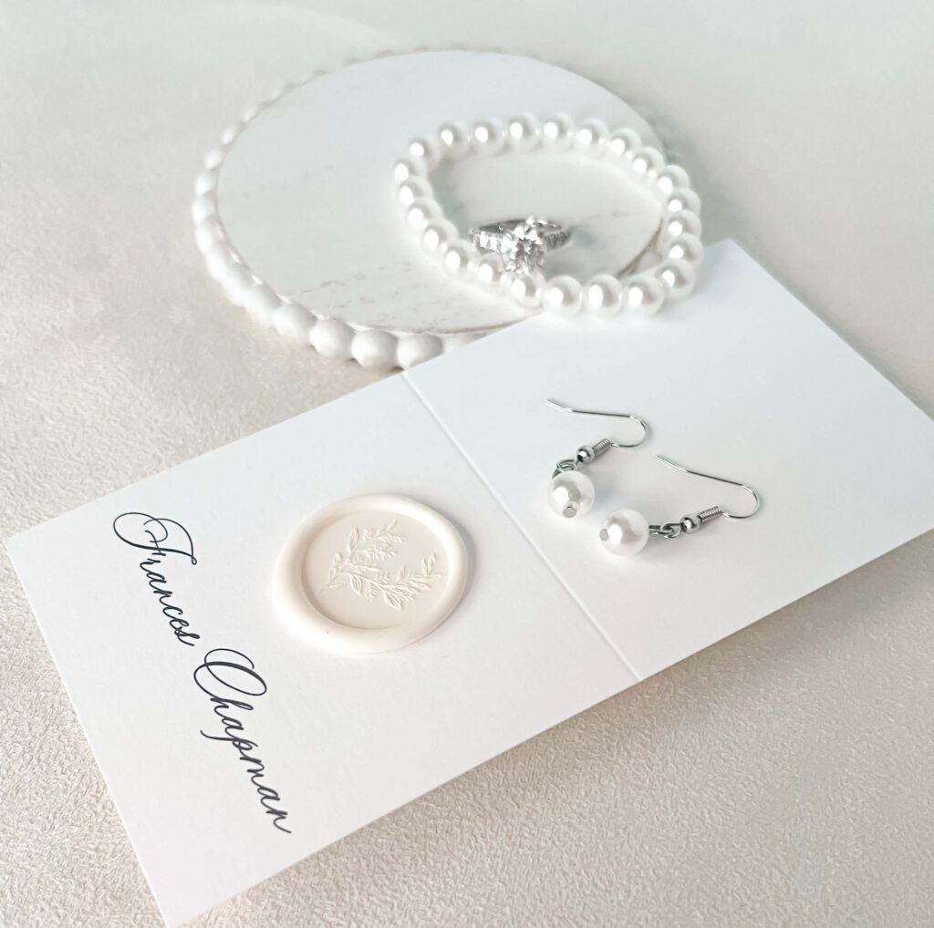 Elegant white escort card with wax seal embellishment