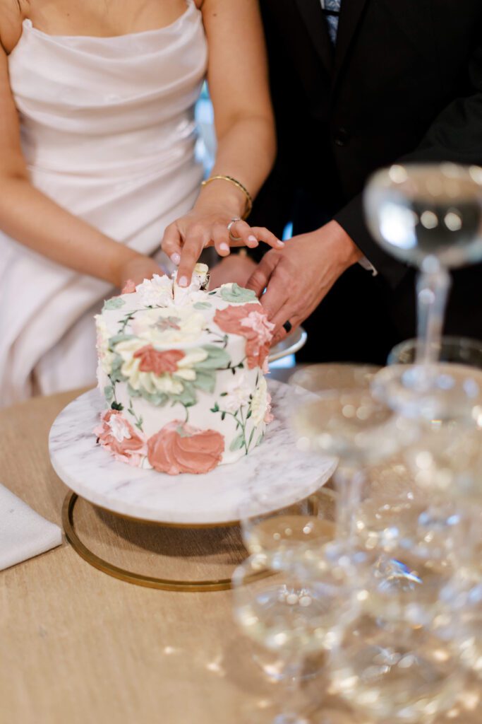 Bride and groom cutting a wedding cake designed with spring flowers