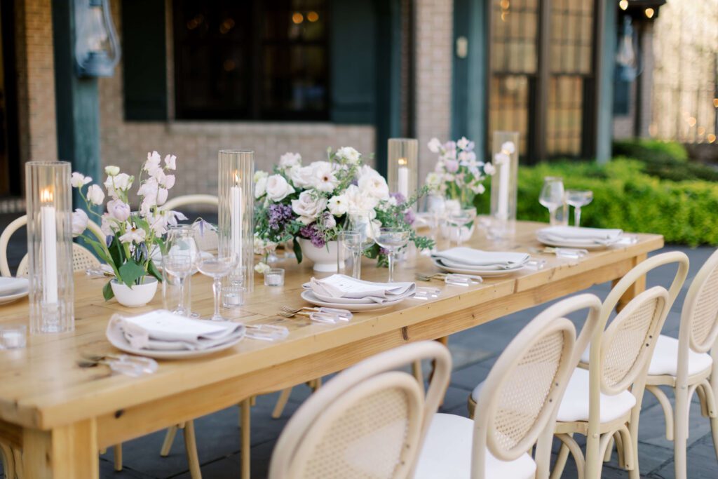 Romantic spring outdoor wedding reception table with purple flowers and candles