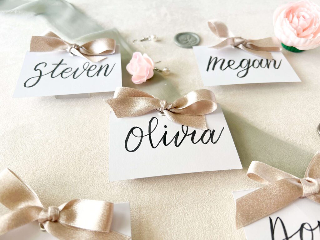 Elegant calligraphed wedding reception place cards with silk bow