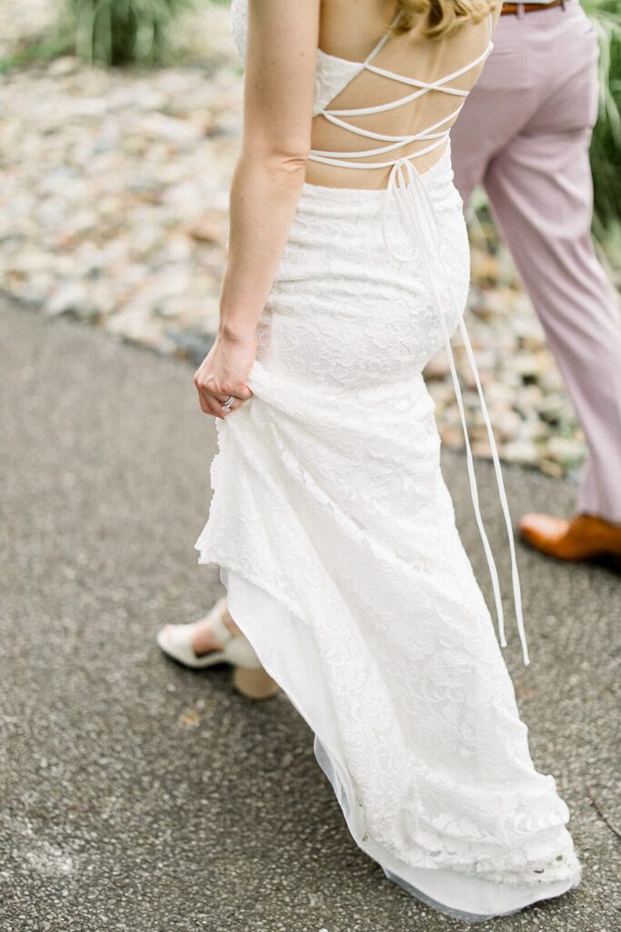 A bride and groom hold hands and walk away from the camera