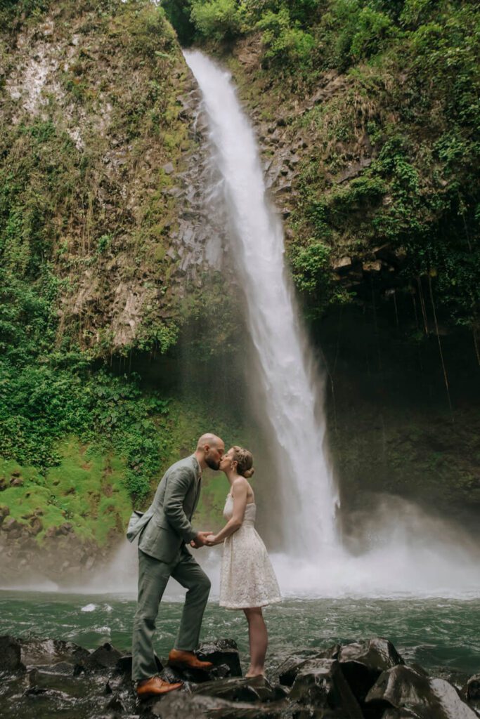 Bride and groom kissing in front of La Fortuna Waterfall during their intimate Costa Rica elopement
