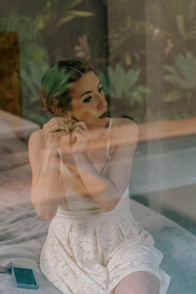 Bride putting on earrings in preparation for her wedding day