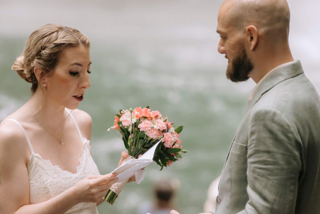 Bride holding a wedding bouquet while reading her vows during a private elopement ceremony