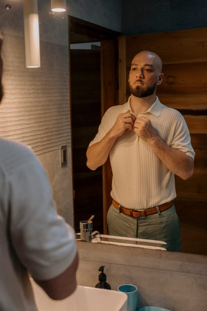 Groom getting ready for his wedding day in front of the mirror
