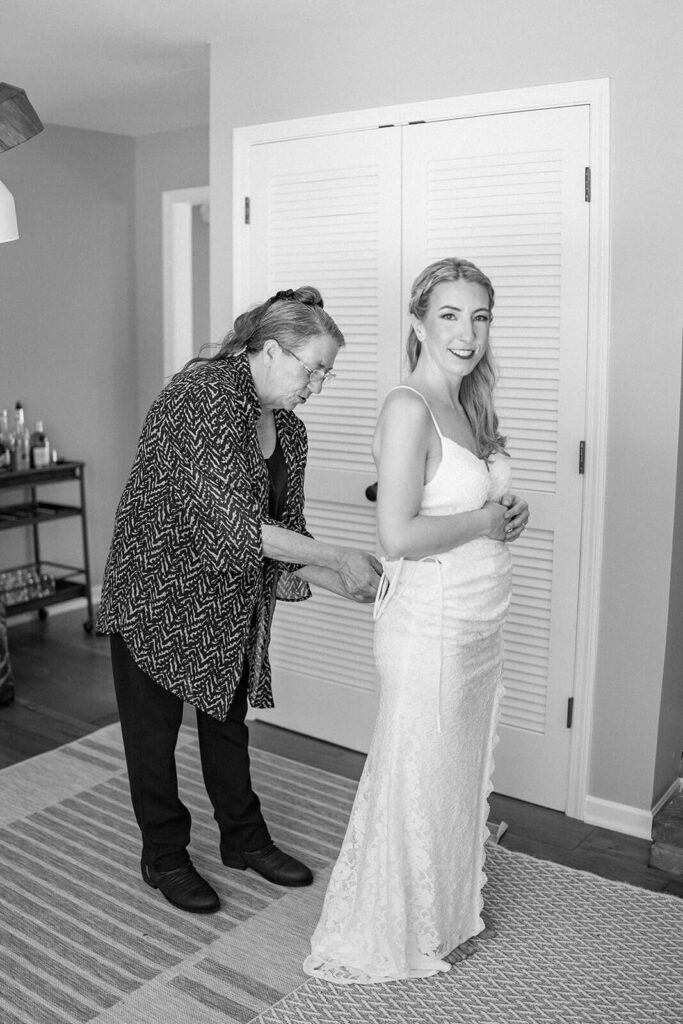 The bride's mother zipping up the bride's dress on her wedding day