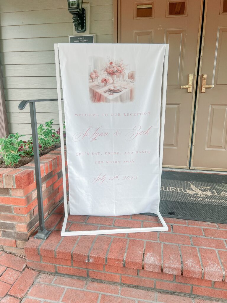 Linen welcome sign for a micro wedding reception featuring watercolor art of a tablescape