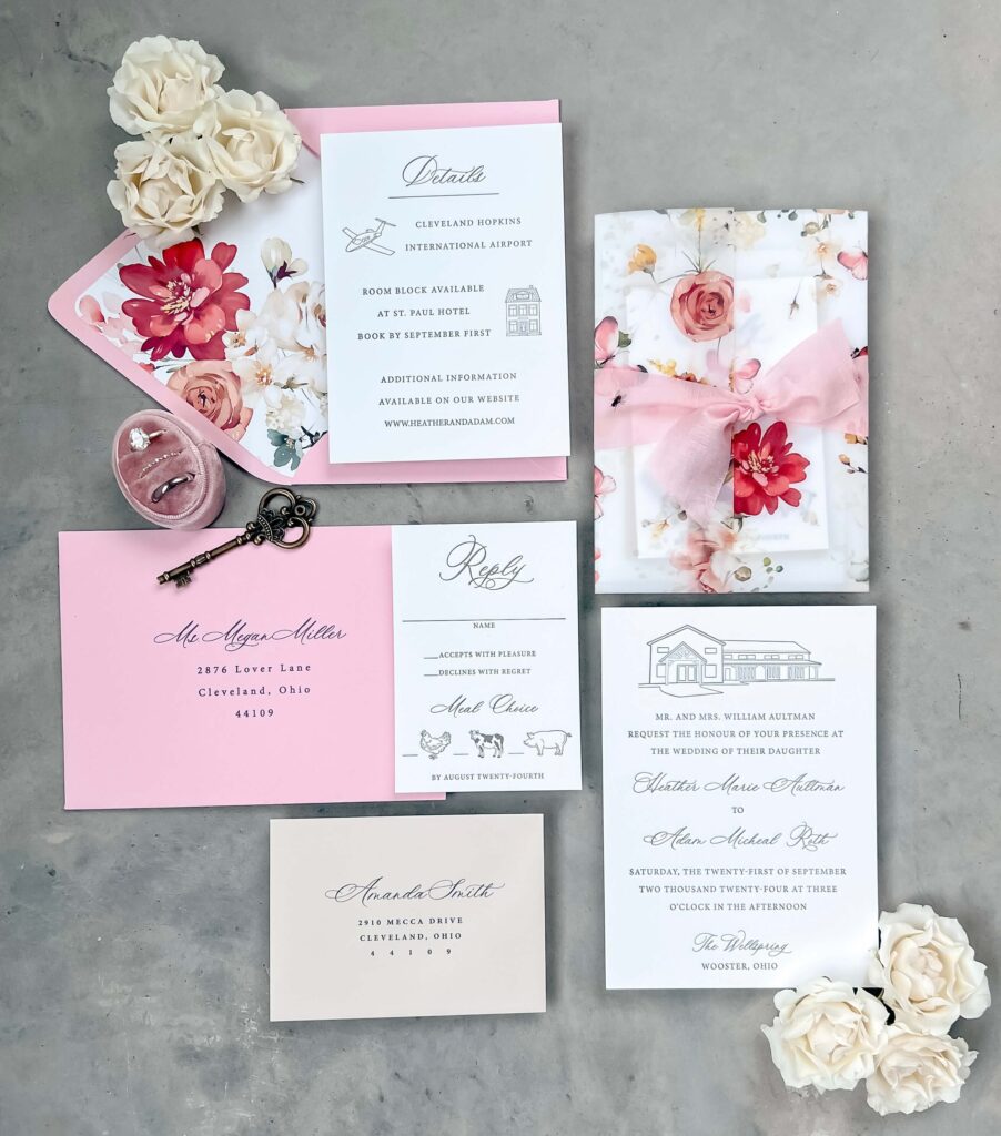 Pink wedding invitation suite featuring a watercolor floral envelope liner and vellum wrap, a venue illustration of The Wellspring, and letterpress printing
