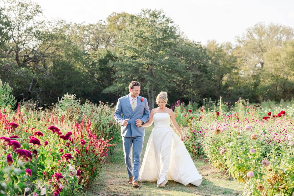 Bride and groom walk through a flower garden