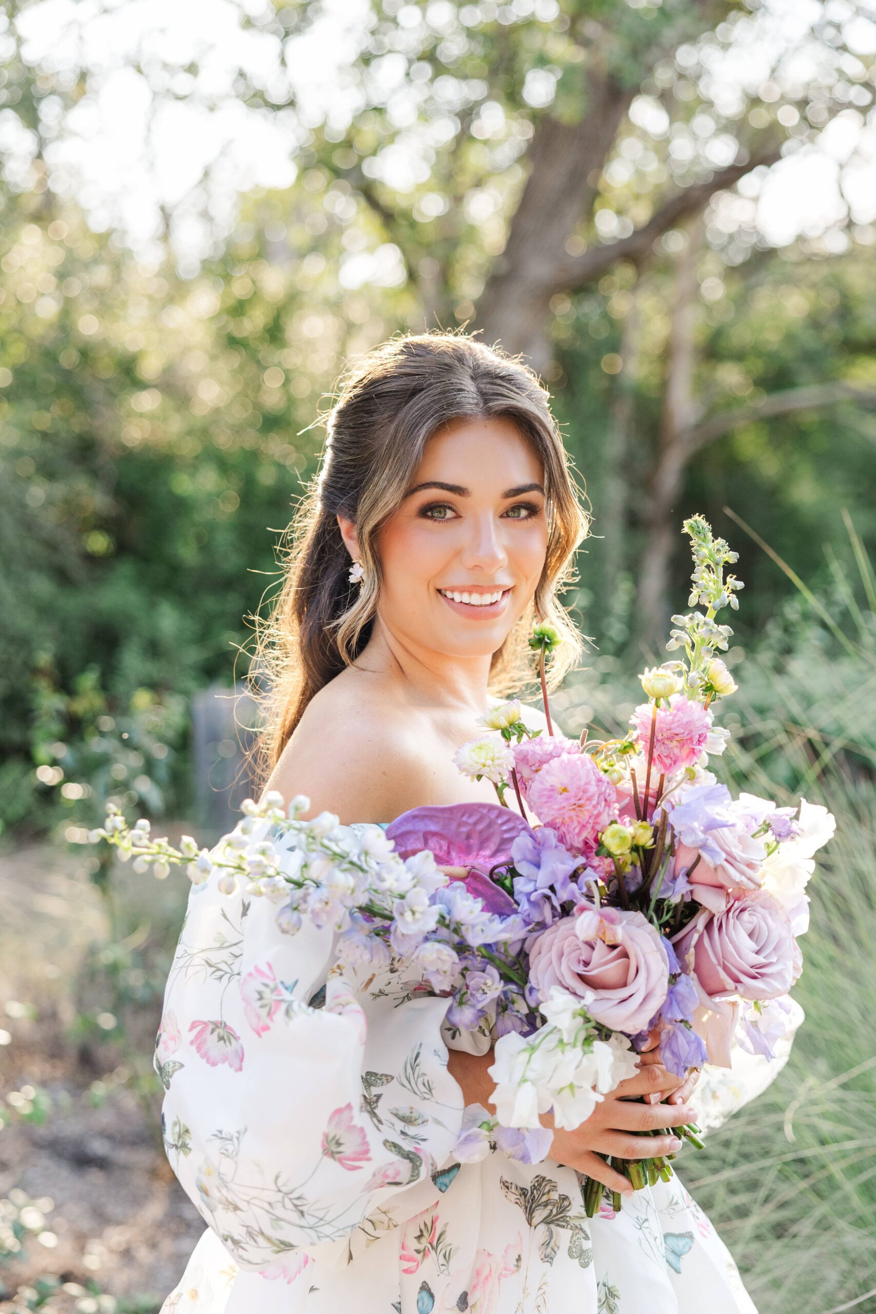 Bride in a romantic floral gown holding an elegant bouquet of bright purple and pink florals