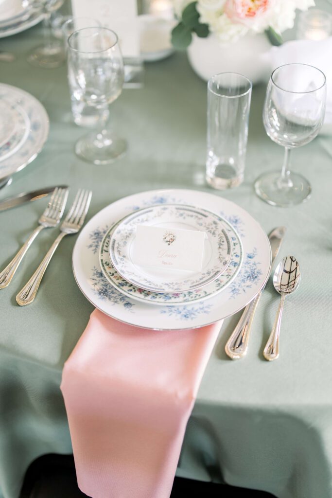 Place card with floral watercolor art sitting upon vintage place settings