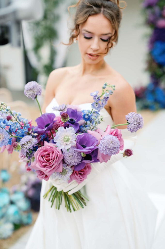 Bride holding a colorful bouquet in shades of purple, pink, and blue