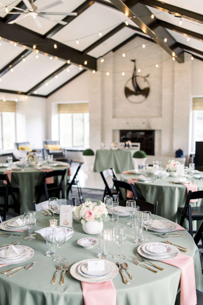 Spring wedding reception with green tablecloths, pink napkins, and vintage plates