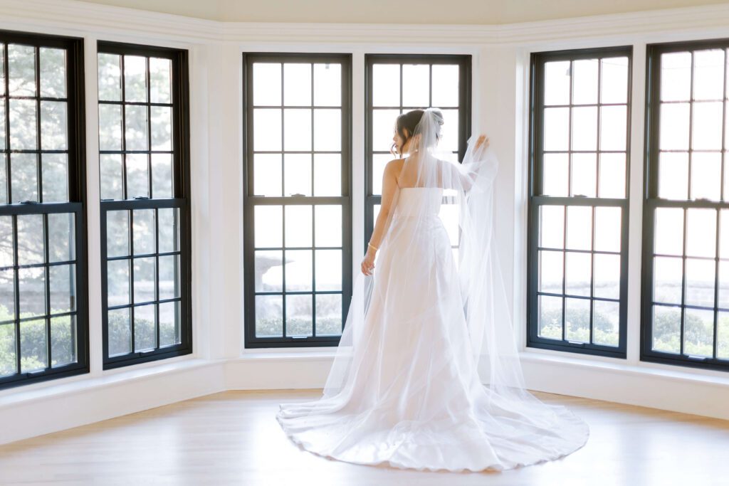 Bride in an all white bridal suite surrounded by windows