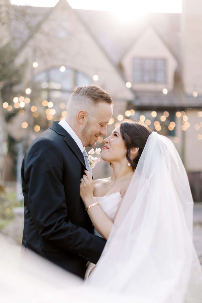 Bride and groom embracing in front of an elegant brick wedding venue