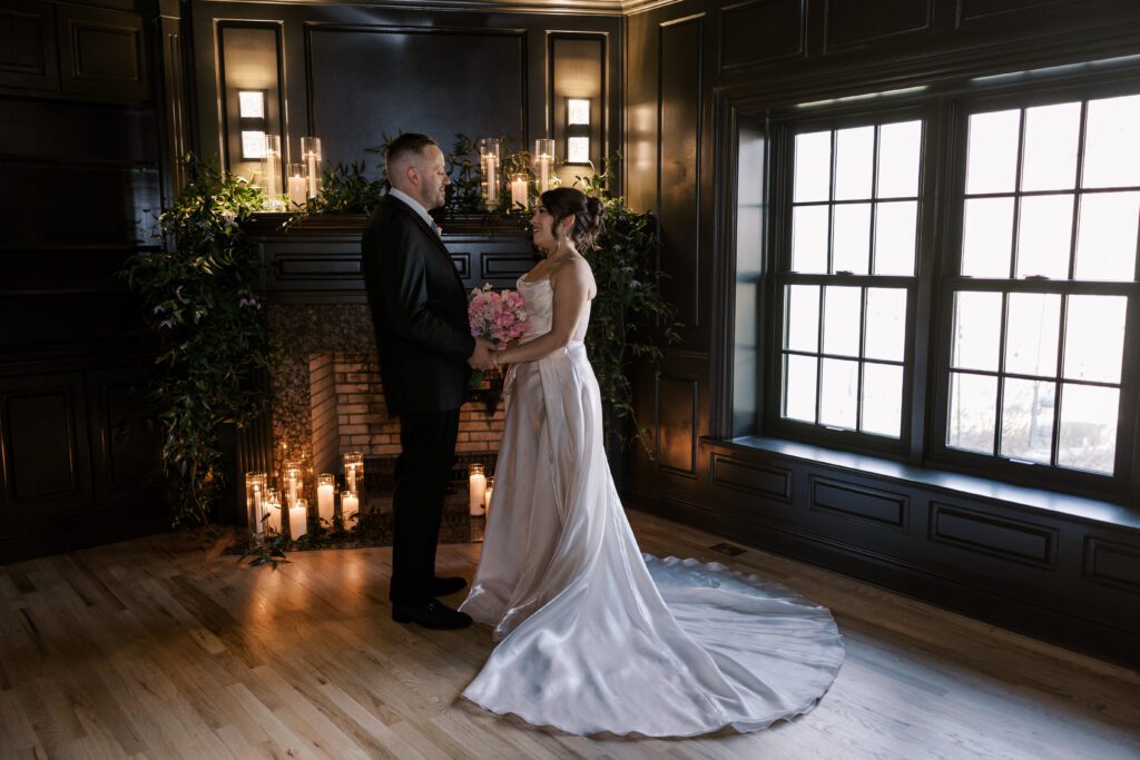 Bride and groom in front of a dark, moody, and romantic candlelit fireplace