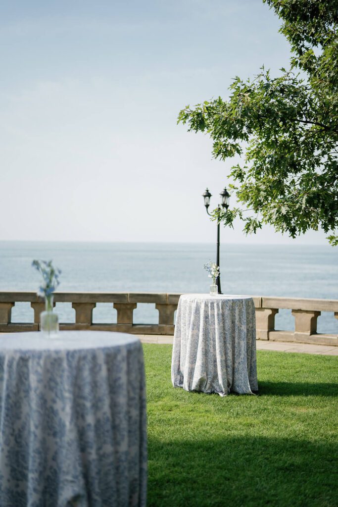 Cocktail hour tables set up by the water at Shoreby Club, decorated in white and blue