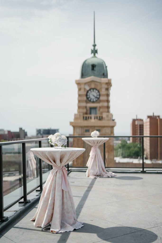 Cocktail hour tables with floral pink tablecloths on a rooftop