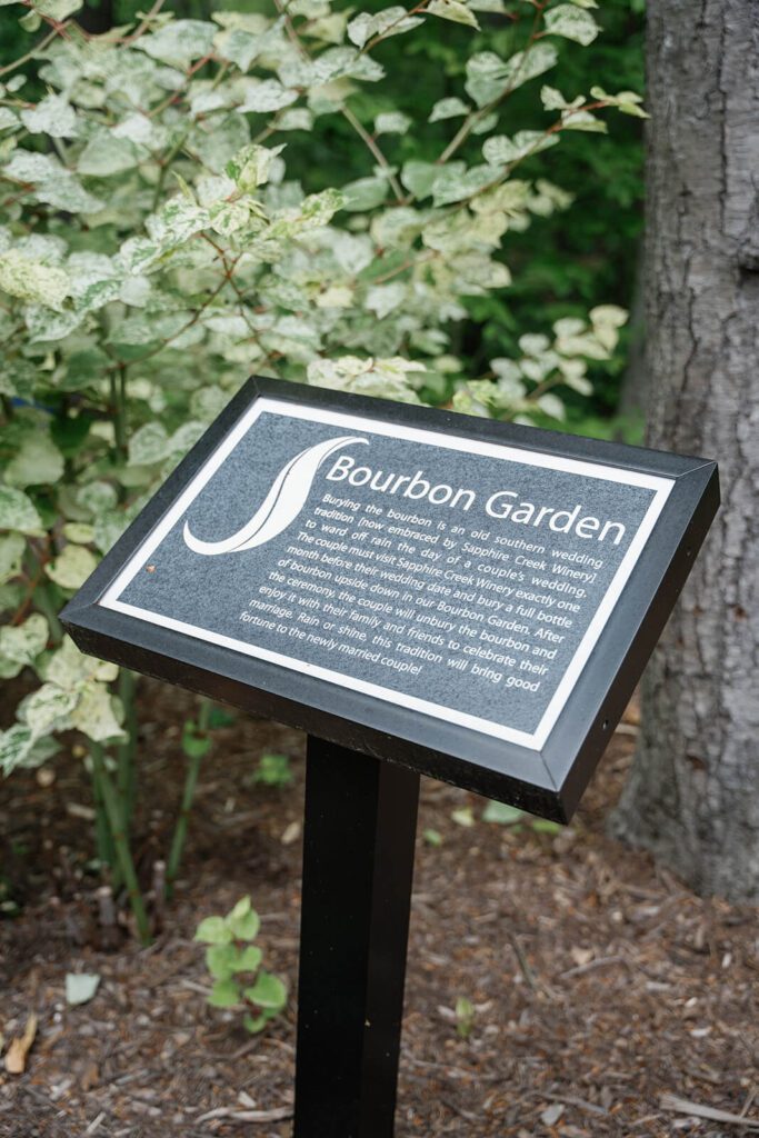 A sign explaining the tradition of the Bourbon Garden. The sign says that the bride and groom must bury bourbon in the garden one month before their wedding to avoid rain.