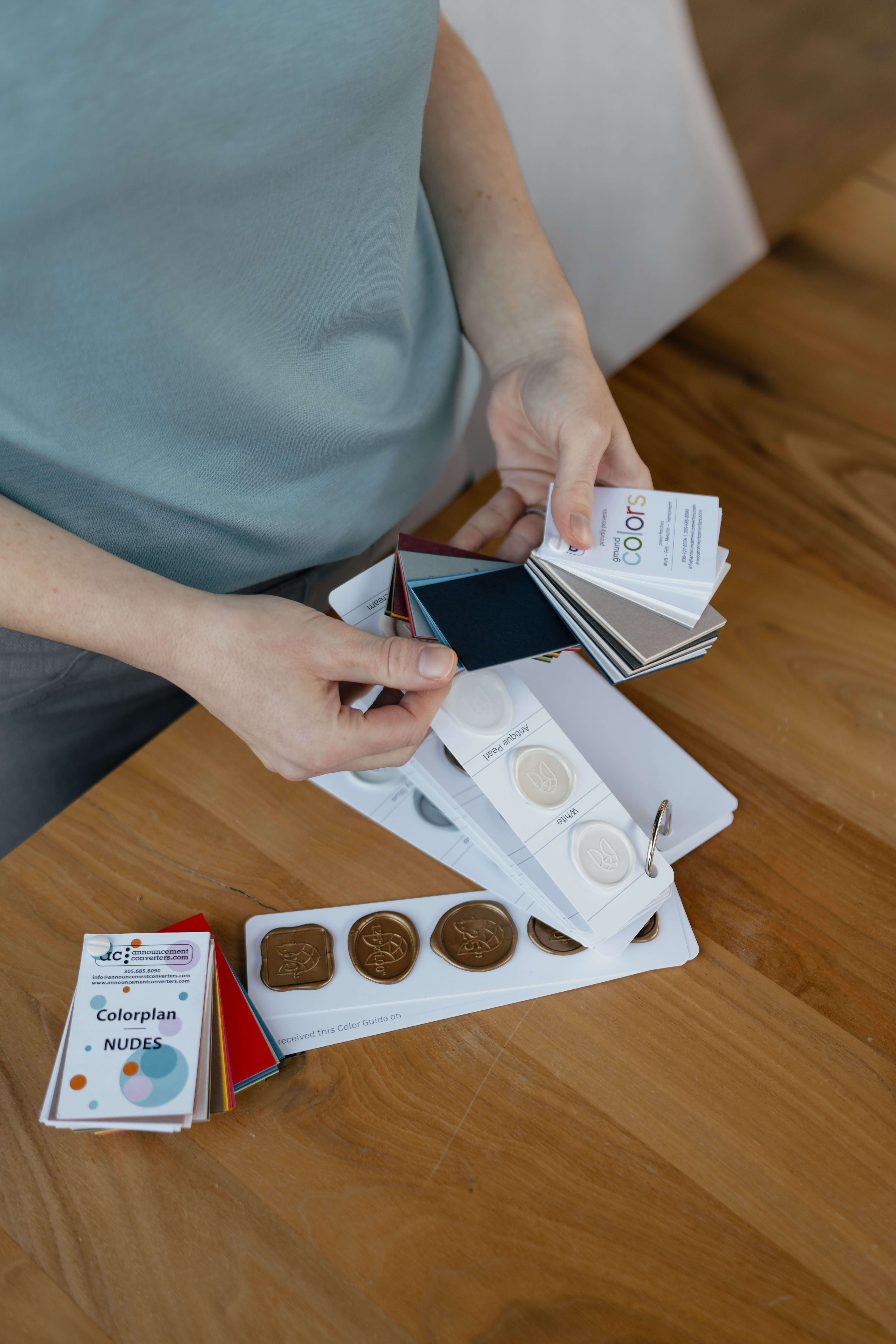 Wedding stationer rifles through wedding invitation swatches and wax seal samples