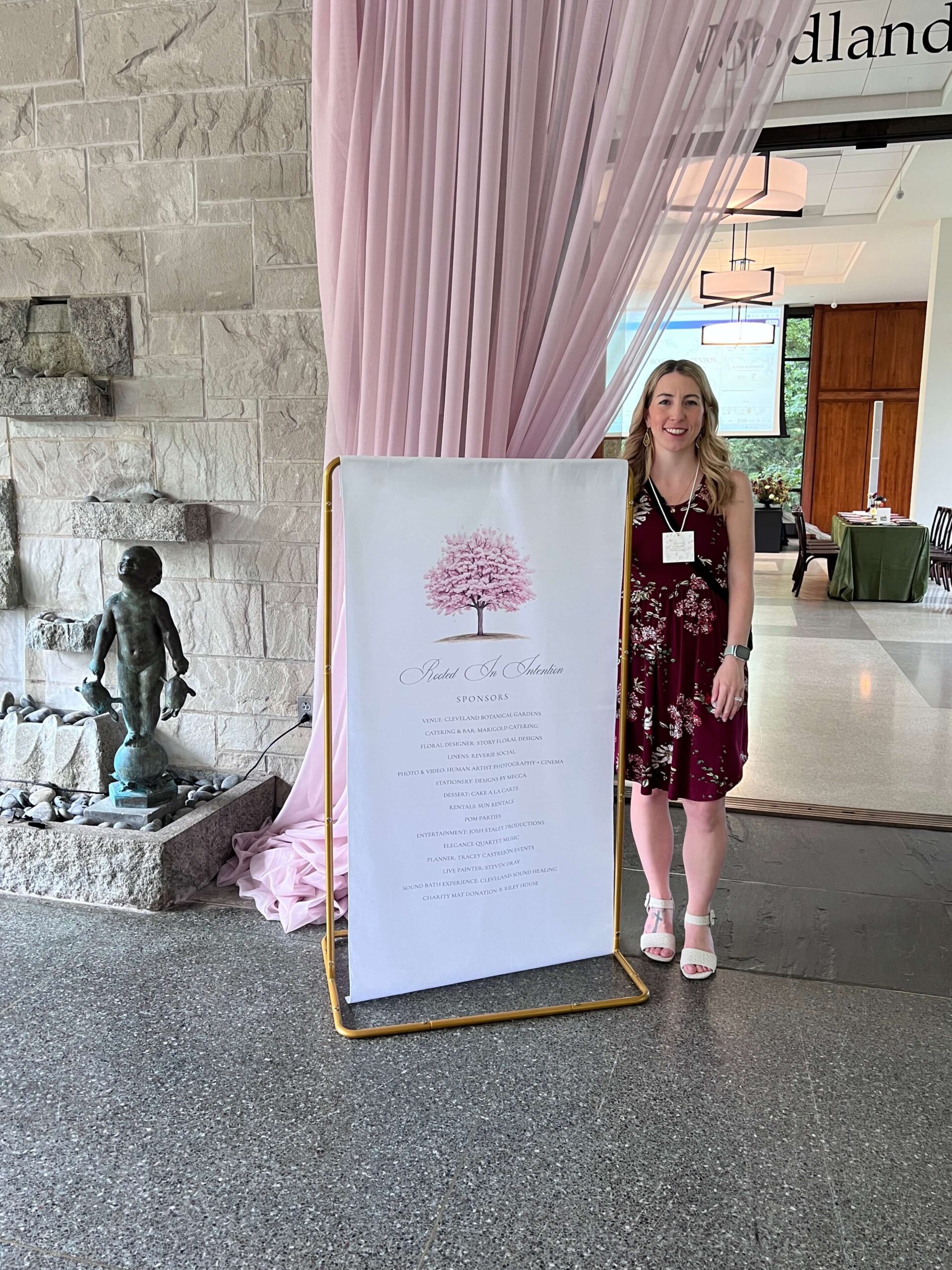 Wedding stationer Designs by Mecca stands by a fabric sign she designed