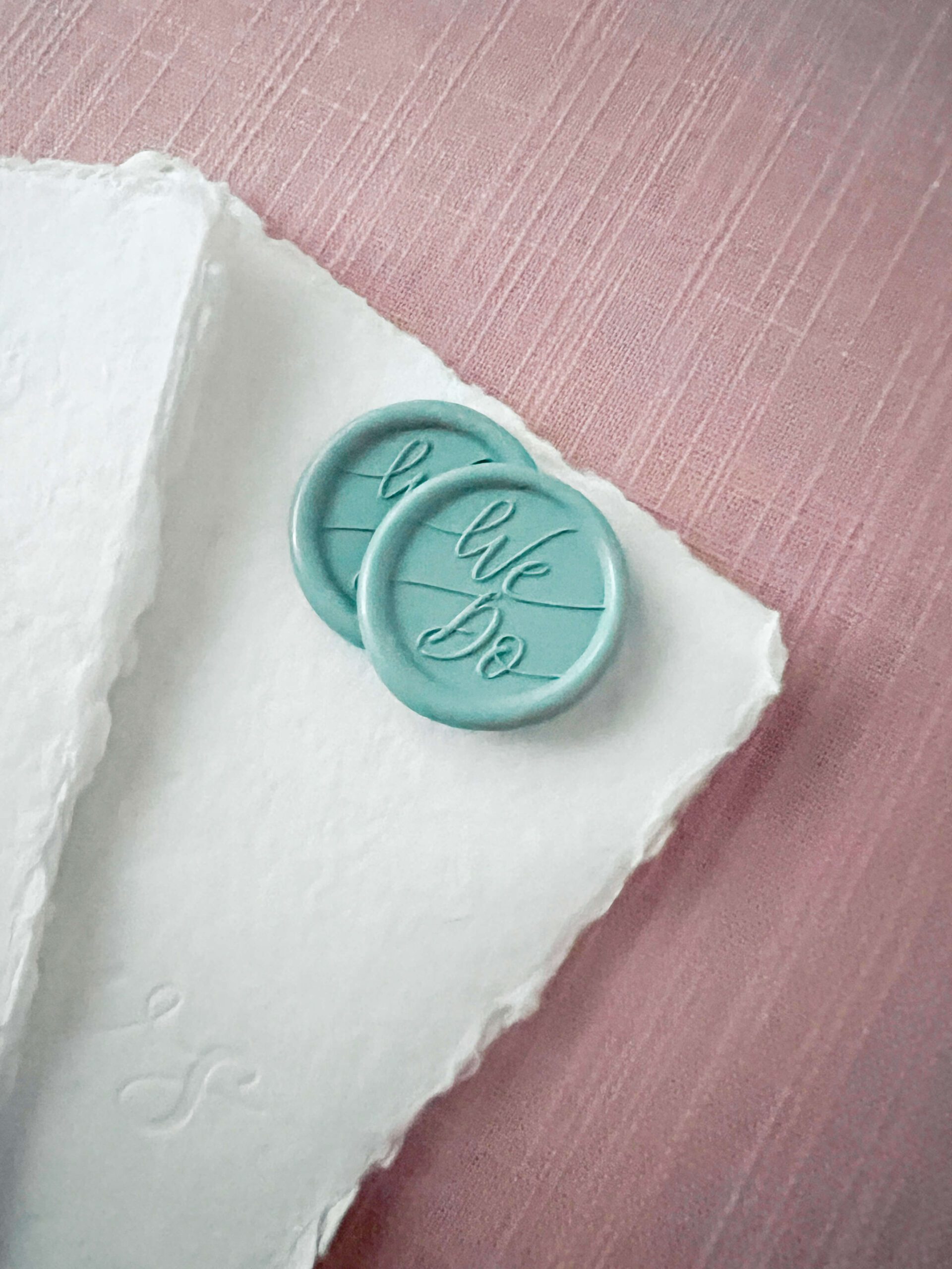 Teal wax seals on top of deckled edge wedding vow books