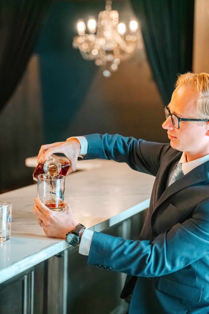 Groom pouring bourbon in the bourbon lounge
