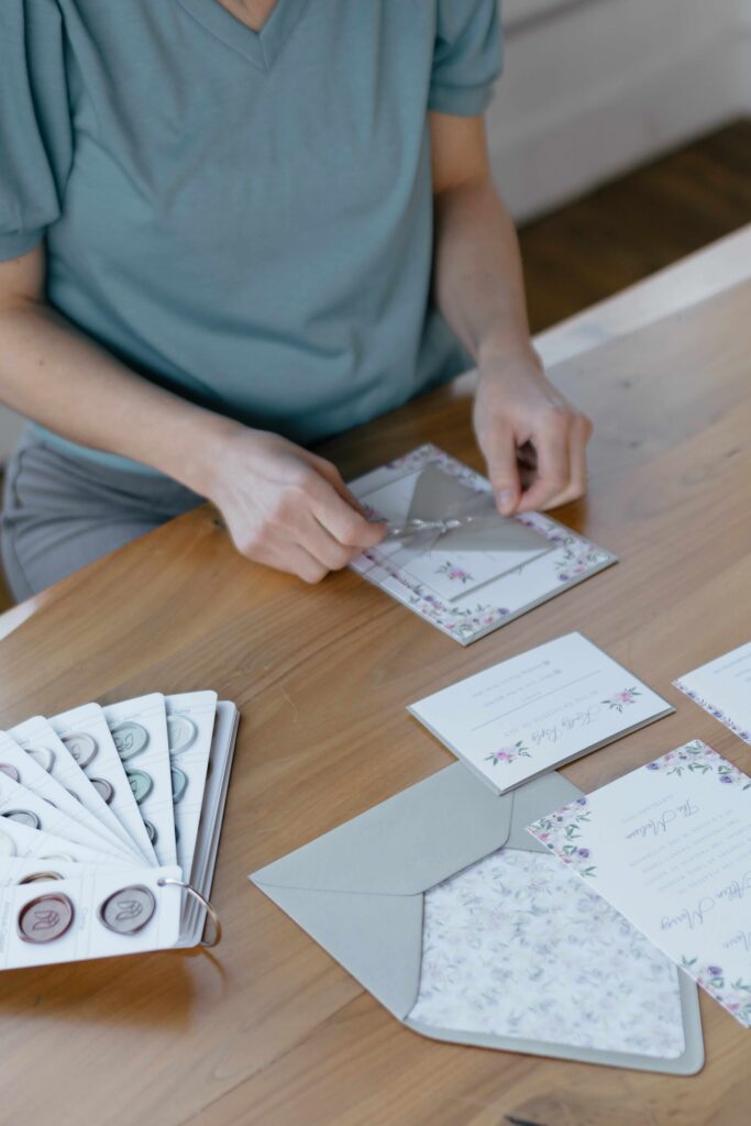 Wedding stationery designer ties a ribbon around a custom wedding invitation suite