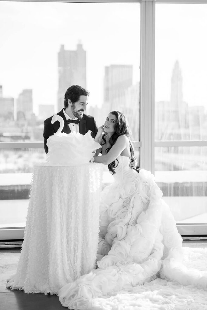 Bride and groom standing by their swan-shaped wedding cake