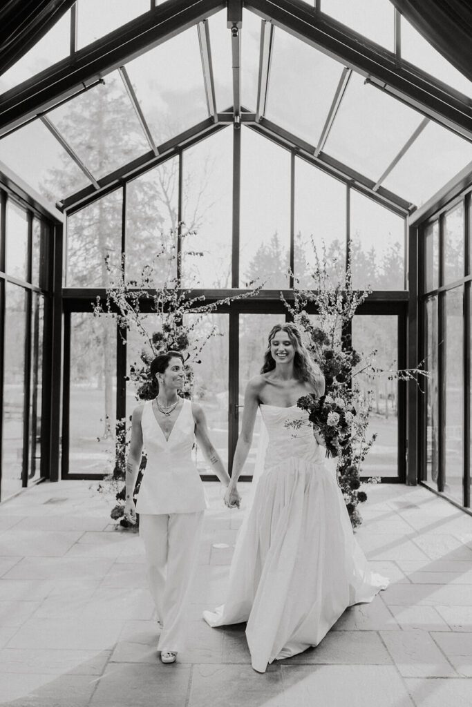 Two brides exiting their wedding ceremony in the Glasshouse at Cedar Lakes Estate