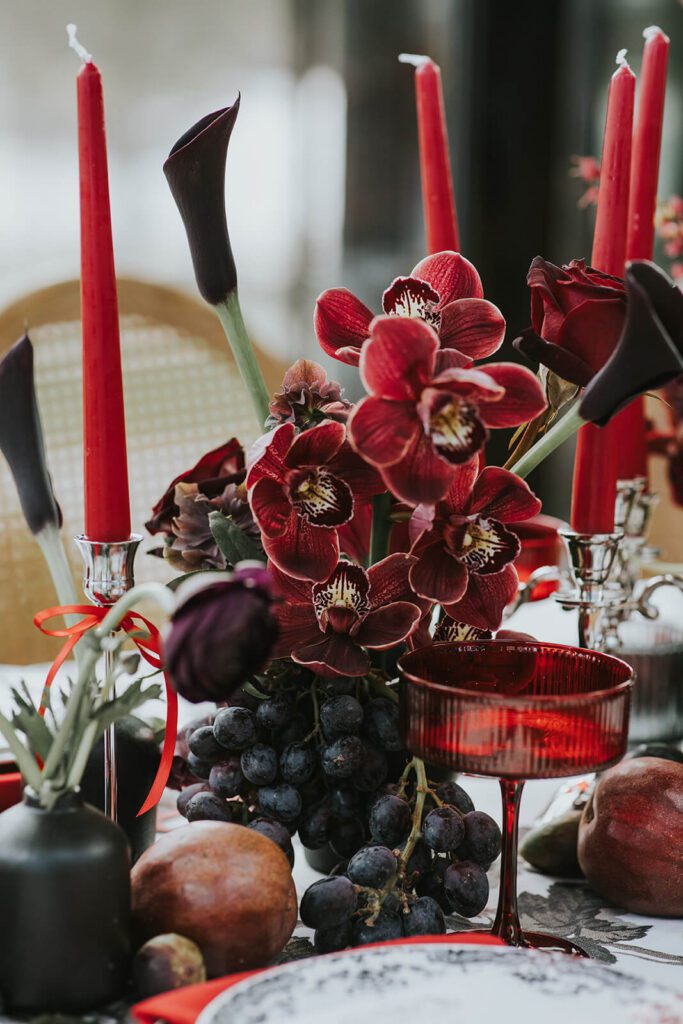 Wedding reception tablescape with deep red orchids, grapes, and figs