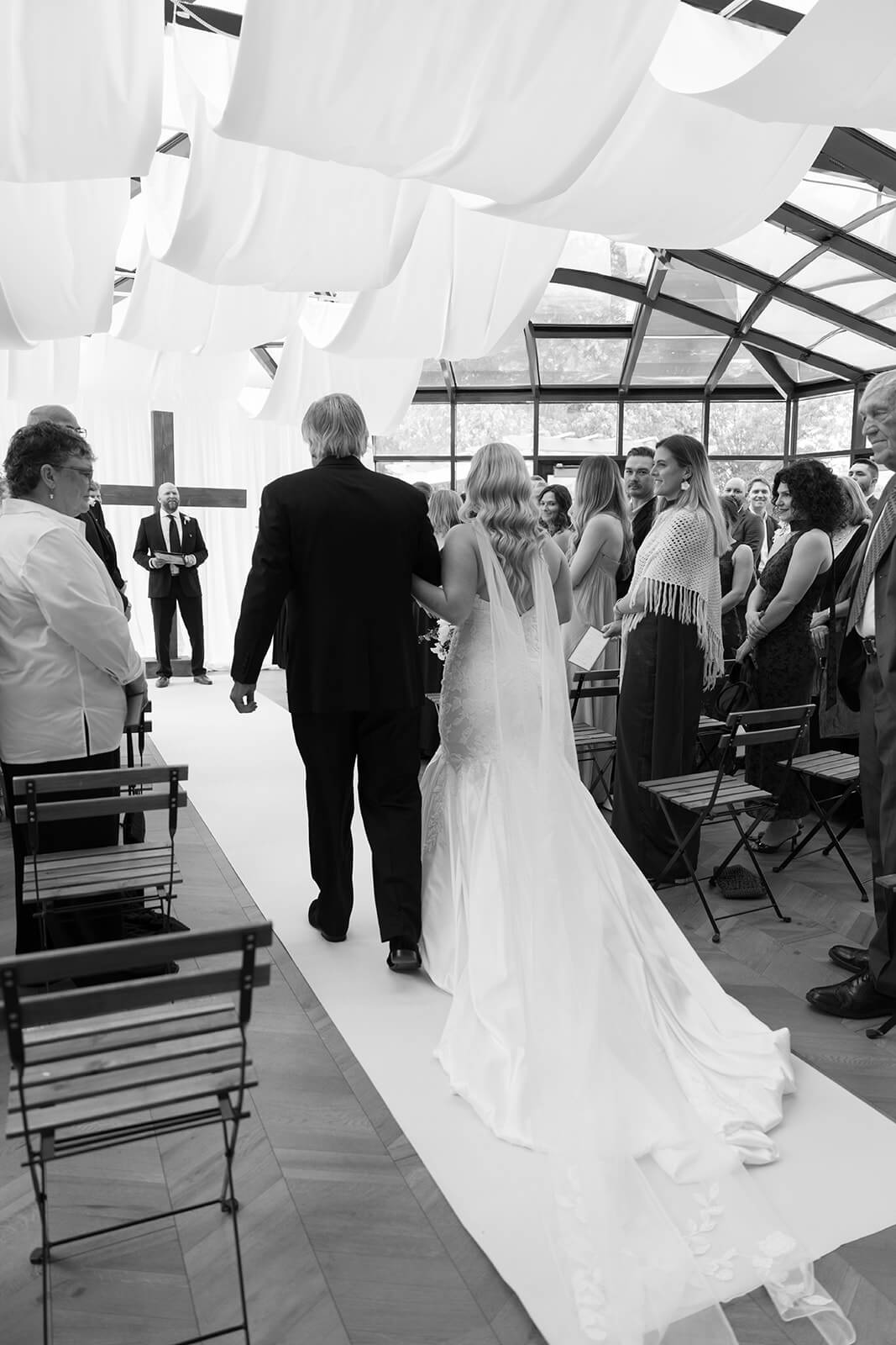 Father of the bride walking the bride down the aisle as guests watch
