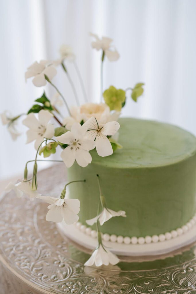Single-tier green wedding cake with whimsical white flowers