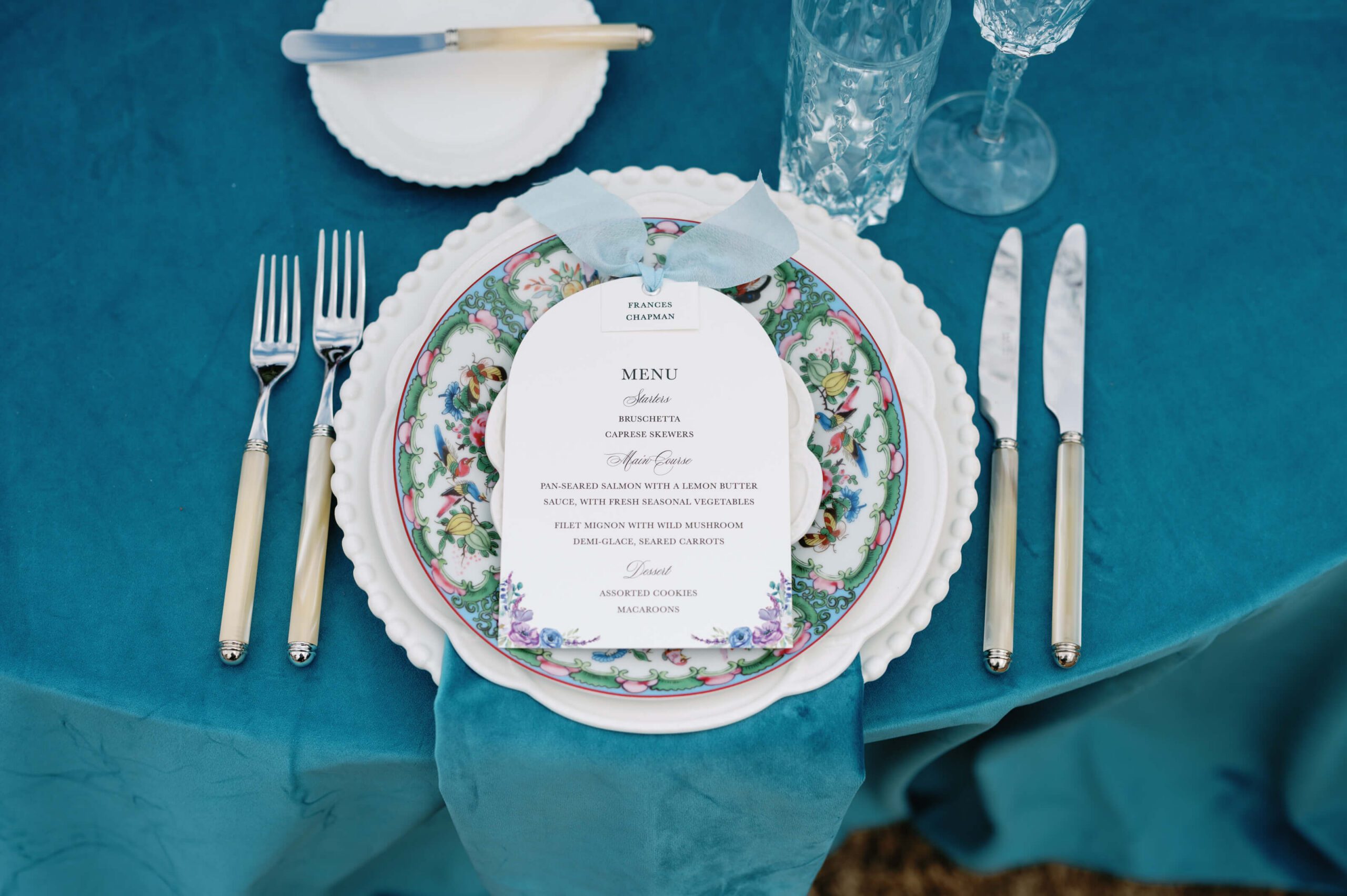 Arched wedding menu card with a blue silk ribbon and watercolor floral details