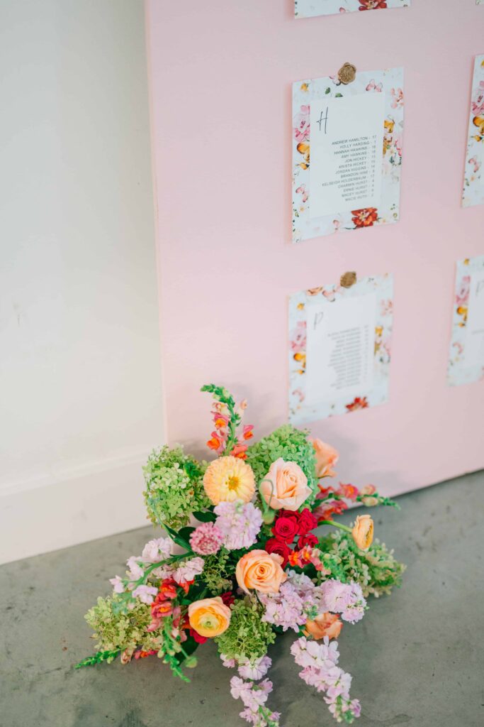 Bright and whimsical floral arrangement at the foot of a seating chart