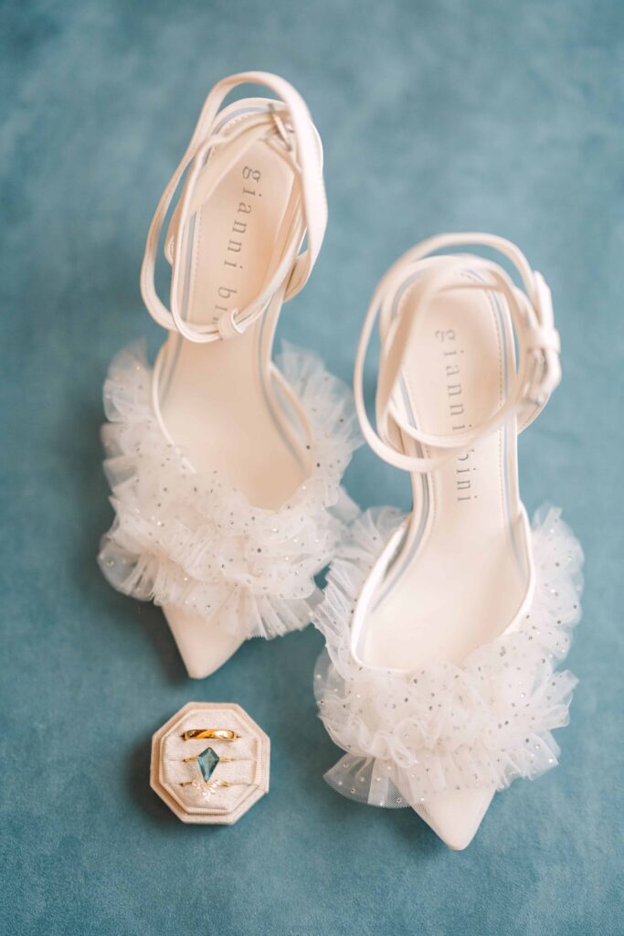 Flat lay of bridal shoes and light blue engagement ring