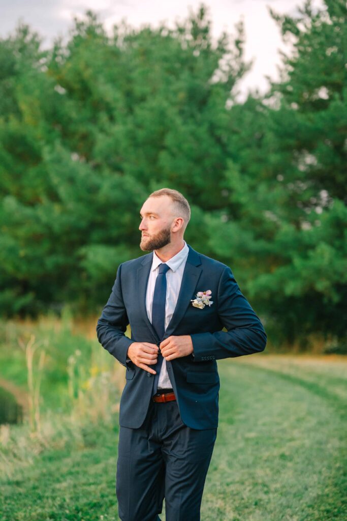 Groom buttoning his navy suit on his wedding day