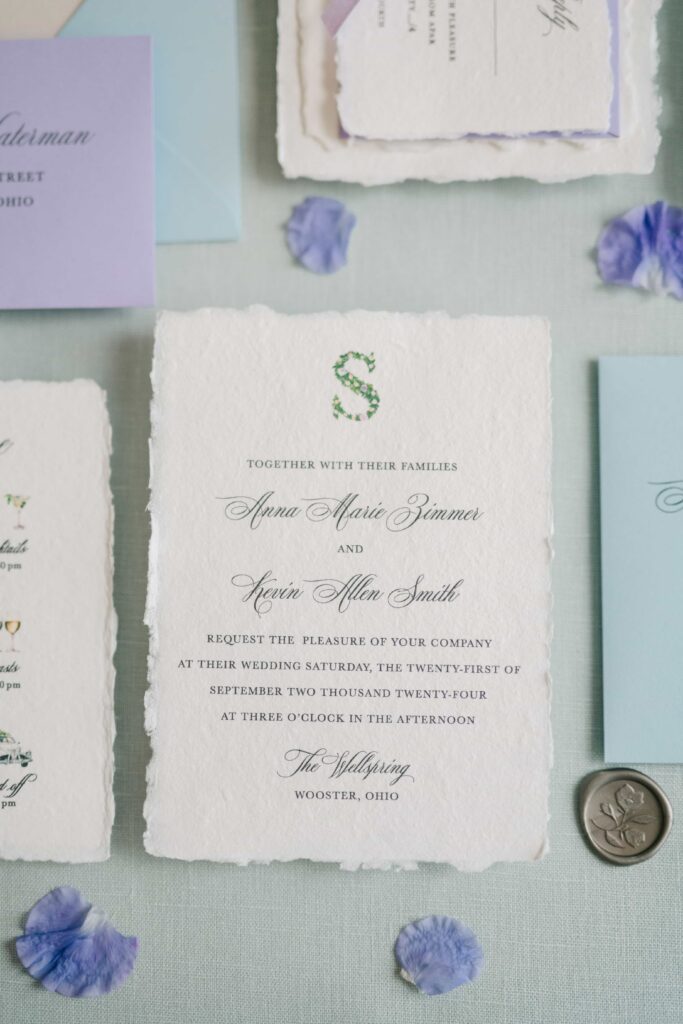 Whimsical deckled edge wedding invitation card with a custom monogram
