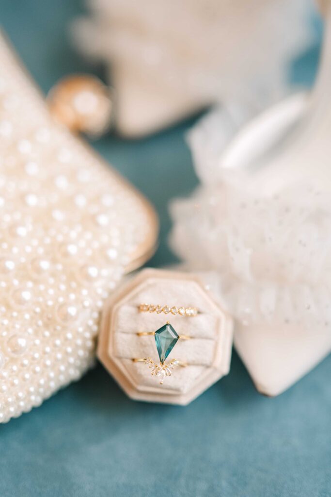 Light blue wedding engagement ring in a box surrounded by gold rings